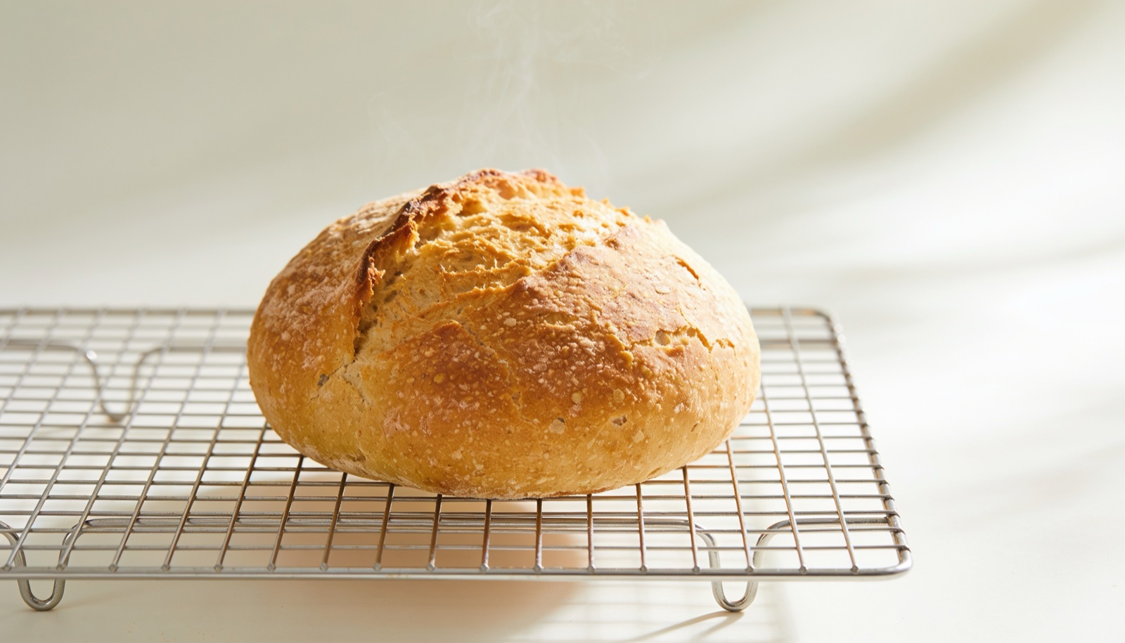 Pão sem glúten dourado esfriando sobre grade metálica em cozinha escura
