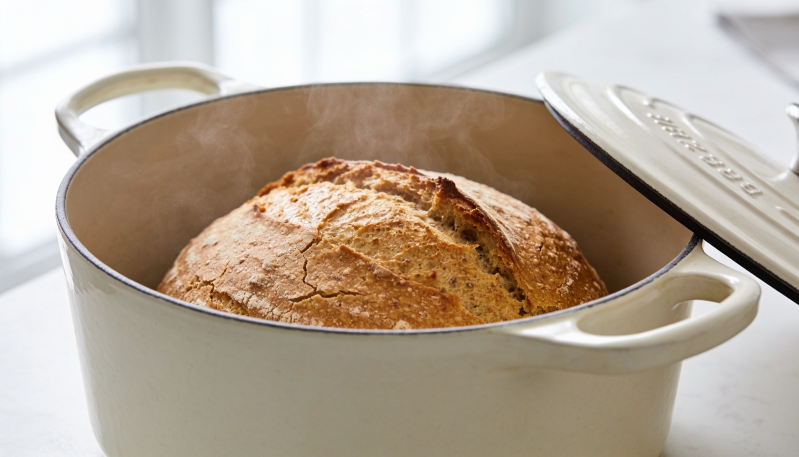 Pão sem glúten dourado assando dentro de uma panela de ferro (dutch oven) com vapor